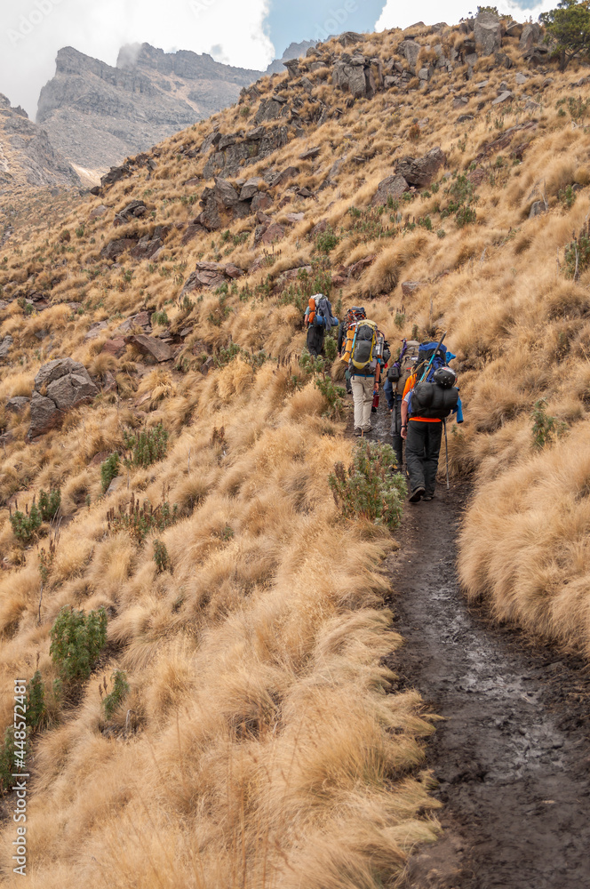 A trail at the foot of a mountain with mountaineers
