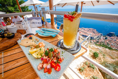 Orange fruit cocktail with snacks on a wooden table over Dubrovnik cityscape view. Croatia.