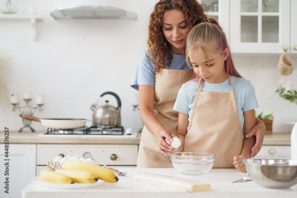 Mother and teen daughter making dough for pastry toghether in kitchen