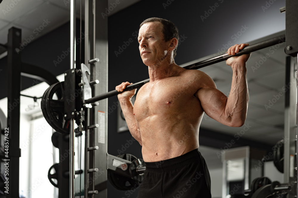 Senior man working out at the gym doing squats Senior man working out at the gym doing squats