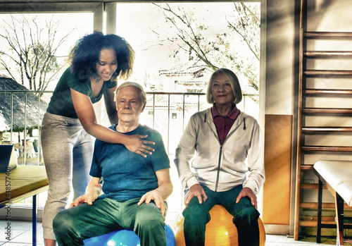 Rehabilitation concept. Elderly couple in a gym supervised by expert african female trainer