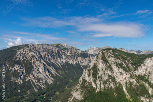 A panoramic view on the Alpine mountain chains in Austria, Hochschwab region. The slopes are partially overgrown with small bushes, higher parts baren. Clear and sunny day. Serenity. Hiking in Alps