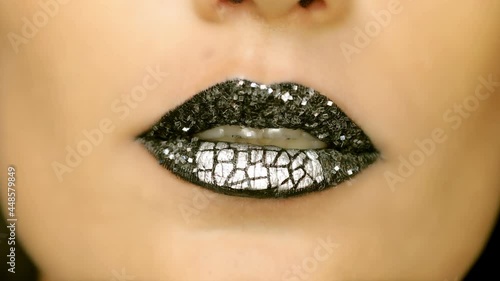 Closeup of a beautiful woman lips with beautiful black makeup sending air kiss . Close up of girl's mouth having flirty emotions and sending air kiss . Fashion concept .	 photo