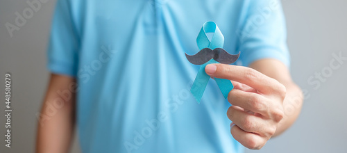 November Prostate Cancer Awareness month, Man holding Blue Ribbon with mustache for supporting people living and illness. Healthcare, International men, Father and World cancer day concept photo