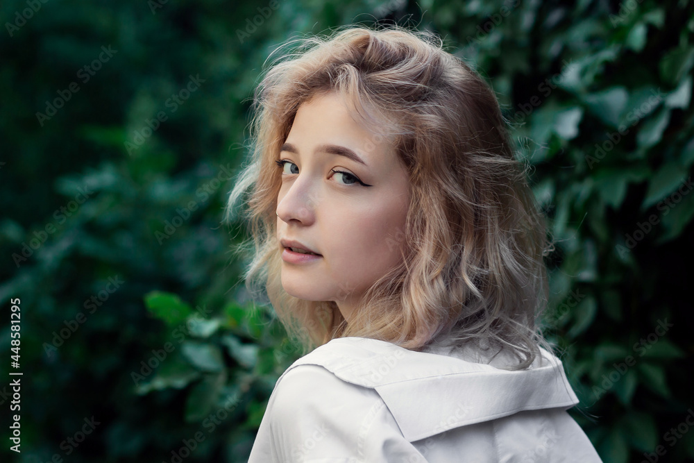 Portrait of a beautiful woman in white clothes on a background of green leaves Portrait of a beautiful woman in white clothes on a background of green leaves