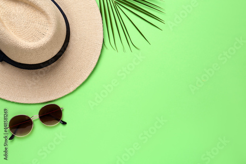 Stylish straw hat  sunglasses and palm leaf on light green background  flat lay. Space for text