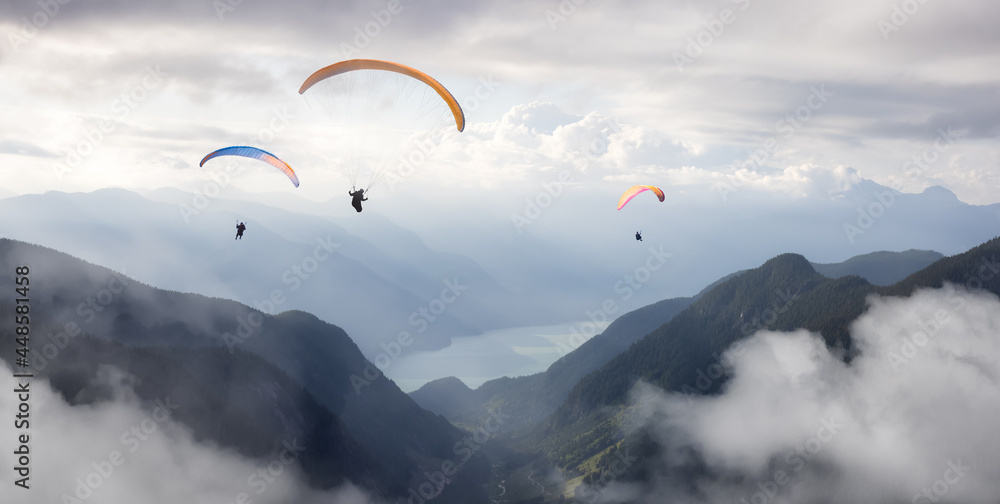 Adventure Composite Image of Paraglider Flying up high in the valley near Mountains. Sunny Summer Cloudy Sky. Aerial Background from British Columbia, Canada. Extreme Sport Concept. Adventure Composite Image of Paraglider Flying up high in the valley near Mountains. Sunny Summer Cloudy Sky. Aerial Background from British Columbia, Canada. Extreme Sport Concept.