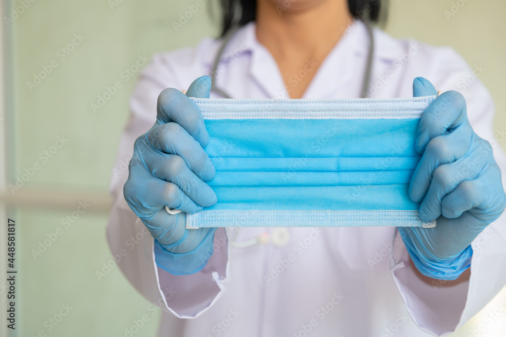 Asian woman in doctor gown or lab coat showing how to correctly wear hygiene surgical mask, demonstrating the method to save health from virus outbreak and dirty air.