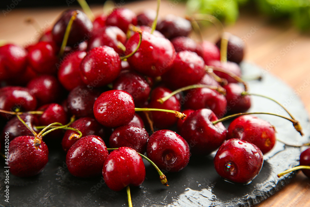 Ripe juicy red cherries lie on a black surface, washed with water Ripe juicy red cherries lie on a black surface, washed with water