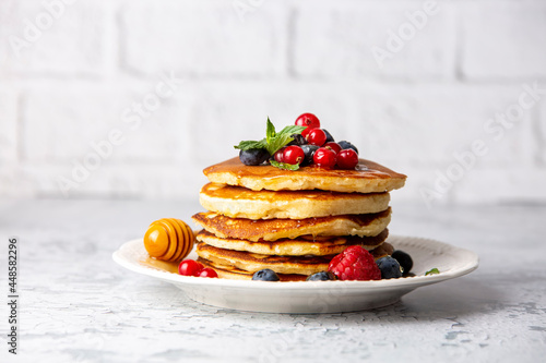 Healthy summer breakfast, homemade classic american pancakes with fresh fruit and honey, morning light gray stone background copy space top view photo