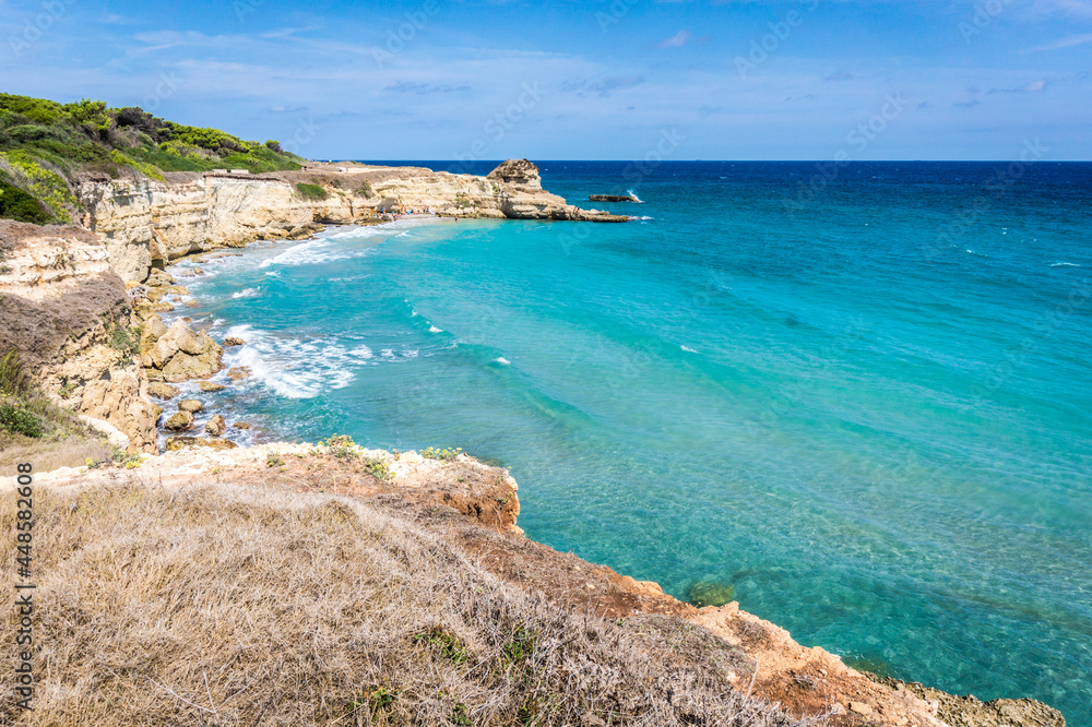 The Punticeddha Beach or Spiaggia Punticeddha of Sant'Andrea, Salento Adriatic sea coast, Apulia, Italy. Beautiful sandy sea coast of Puglia with blue water, cliffs on a Summer day, top view