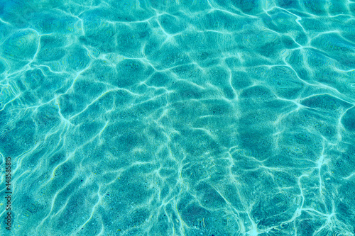 Turquoise Pure clear water in the sea  sun glare  waves and sea sand. Calm sea water background