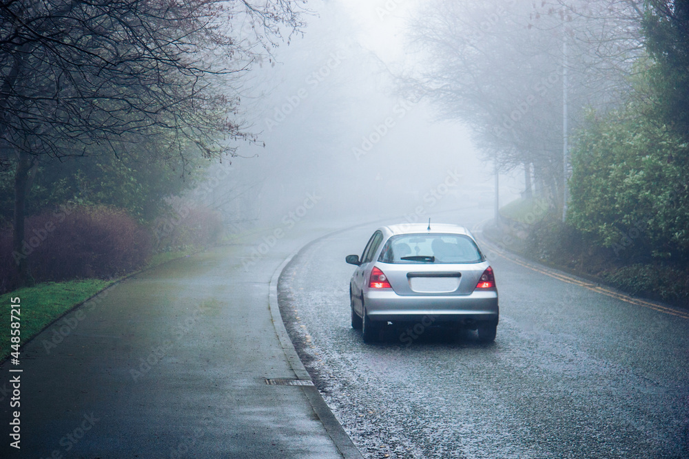 A car moving in a fog in a city - concept of a dangerous hazardous driving conditions, limited visibility A car moving in a fog in a city - concept of a dangerous hazardous driving conditions, limited visibility