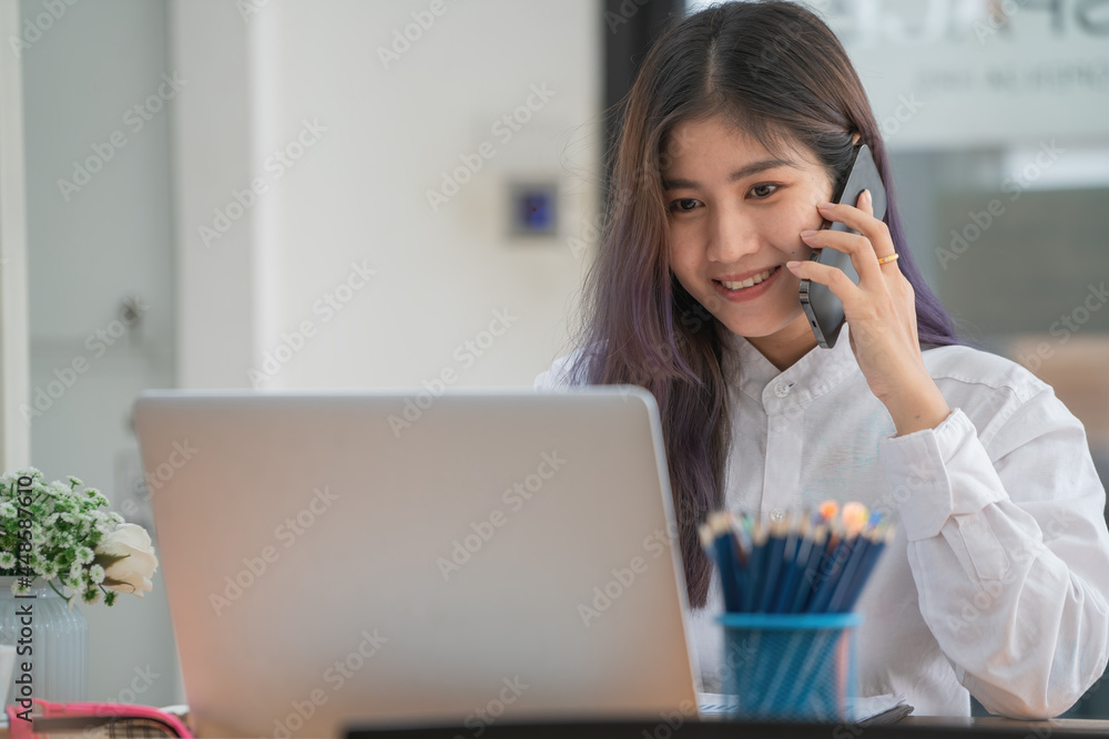 Portrait of businesswoman talking on the phone while working at a worktable in an office room. Portrait of businesswoman talking on the phone while working at a worktable in an office room.