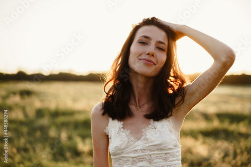 Young woman standing in a field at sunrise enjoying view
