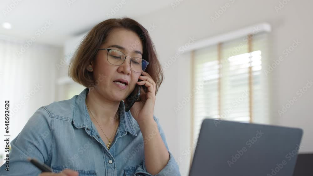 Asia adult people or SME owner woman leader moody sitting tired busy phone call work on laptop computer at desk house office think worry concern give advice on distance job crisis corporate trouble. Asia adult people or SME owner woman leader moody sitting tired busy phone call work on laptop computer at desk house office think worry concern give advice on distance job crisis corporate trouble.
