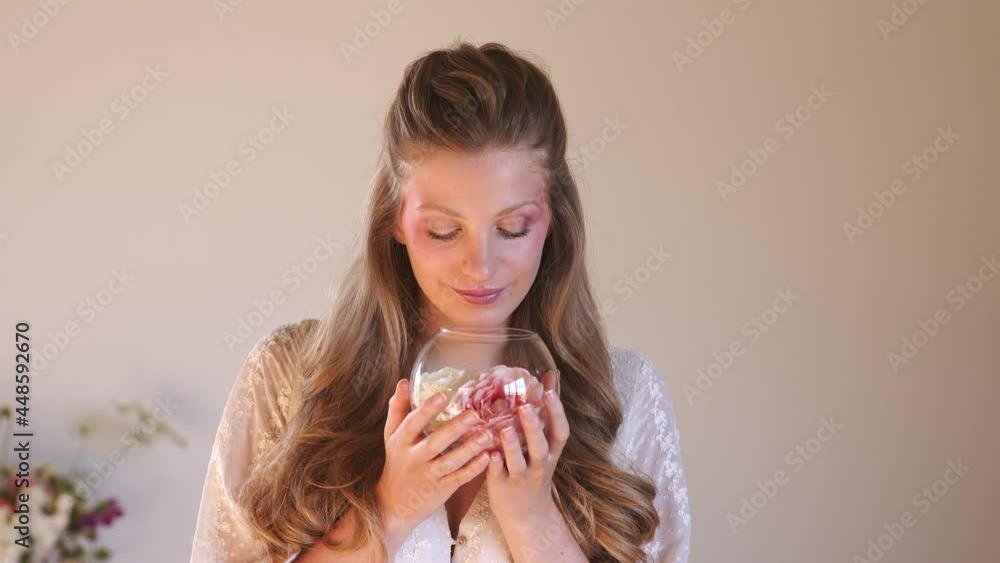 Beautiful blond woman smelling roses in glass bowl Beautiful blond woman smelling roses in glass bowl