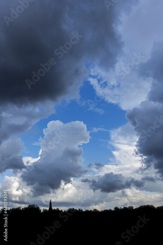 Gap in white and grey cumulus clouds showing patch of blue sky on a rainy day in summer