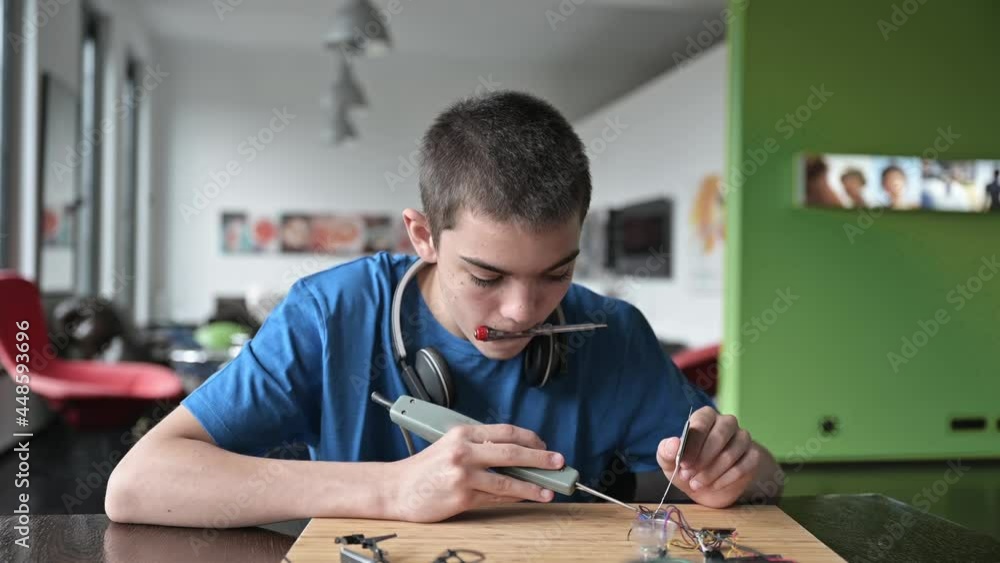 Teenager fixing wires with soldering iron Teenager fixing wires with soldering iron
