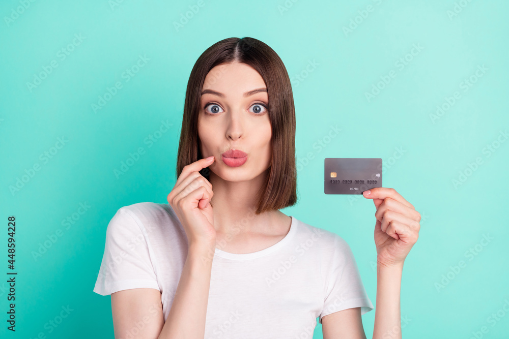 Photo of amazed shocked young woman hold finger face credit card payment isolated on teal color background Photo of amazed shocked young woman hold finger face credit card payment isolated on teal color background