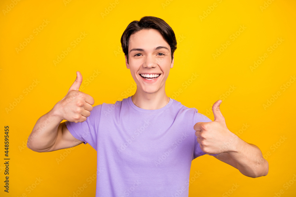 Portrait of attractive cheerful successful guy showing double thumbup ad trust isolated over bright yellow color background Portrait of attractive cheerful successful guy showing double thumbup ad trust isolated over bright yellow color background