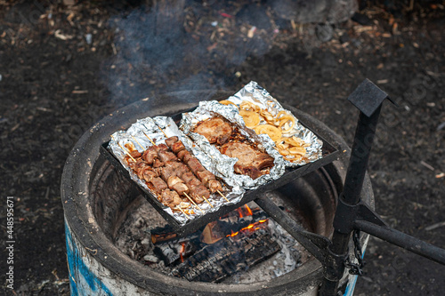 Pork kebab, pork steaks and onions are grilled on the foil over a campfire.