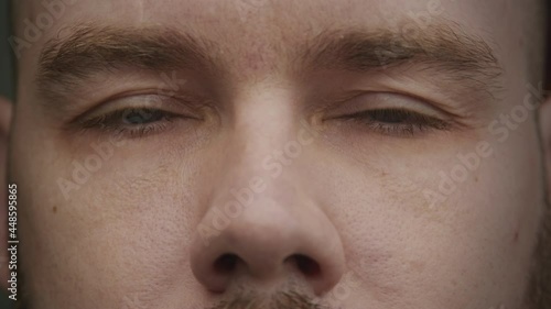 Adult caucasian man closing eyes shut and opening them in slow motion photo