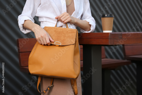 Young woman with stylish backpack in outdoor cafe, closeup