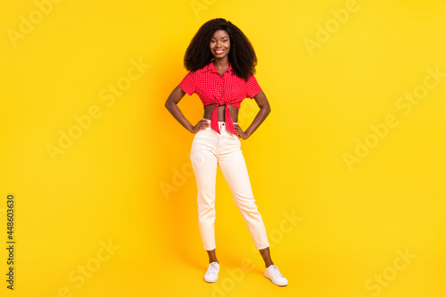 Full length body size view of lovely cheerful slender fashionable girl hands on hips isolated over bright yellow color background © deagreez