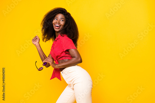 Photo of profile side photo of dark skin nice happy young woman look empty space wear sunglass isolated on yellow color background