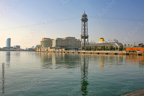 View accross the port towards the cruise terminal, with cruise ships docked, the cable car tower, and reflections in the mediteranean sea on a beautiful summer day, Barcelona, Catalonia, Spain.