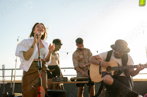 Fotografia Modern music band of singer and guitarist performing at rooftop party or concert