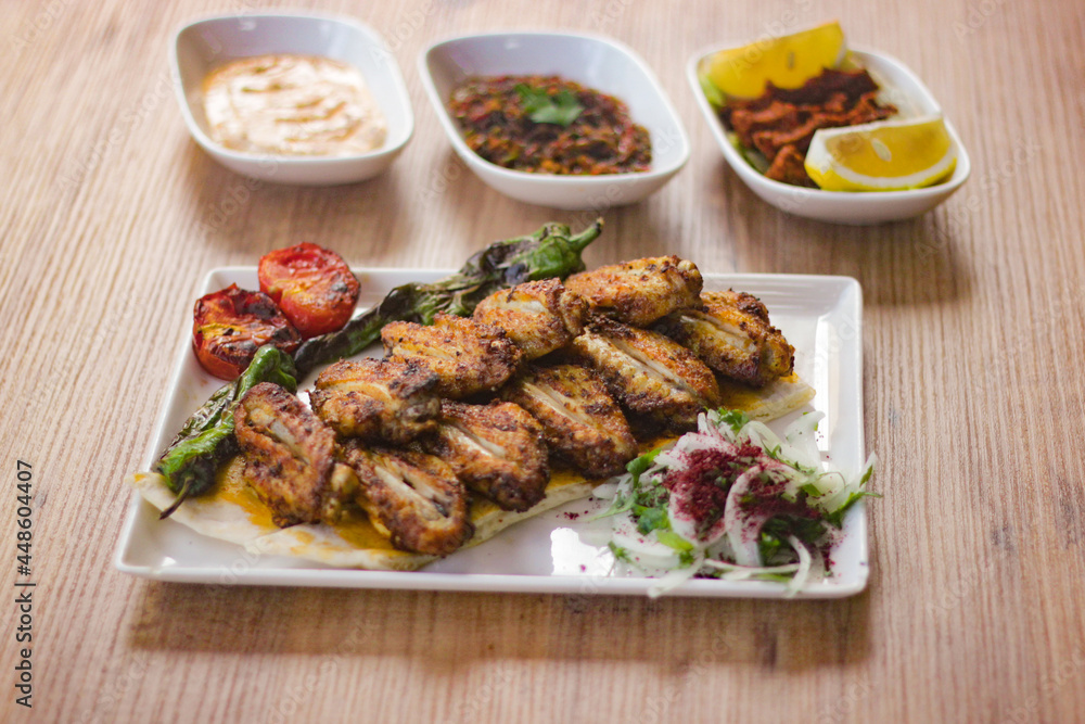 grilled chicken wings with vegetables, mezzes and salads on wooden table. turkish barbecue. grilled chicken wings with vegetables, mezzes and salads on wooden table. turkish barbecue.