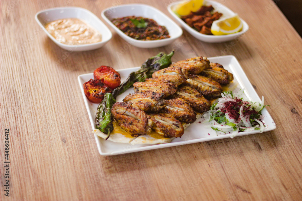 grilled chicken wings with vegetables, mezzes and salads on wooden table. turkish barbecue. grilled chicken wings with vegetables, mezzes and salads on wooden table. turkish barbecue.