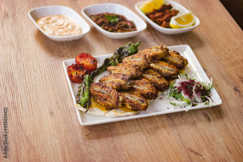 grilled chicken wings with vegetables, mezzes and salads on wooden table. turkish barbecue. 