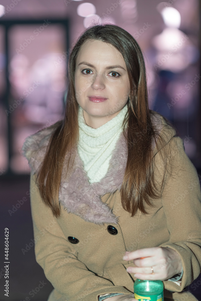 Young beautiful girl in an autumn coat on the street of the night city. Young beautiful girl in an autumn coat on the street of the night city.