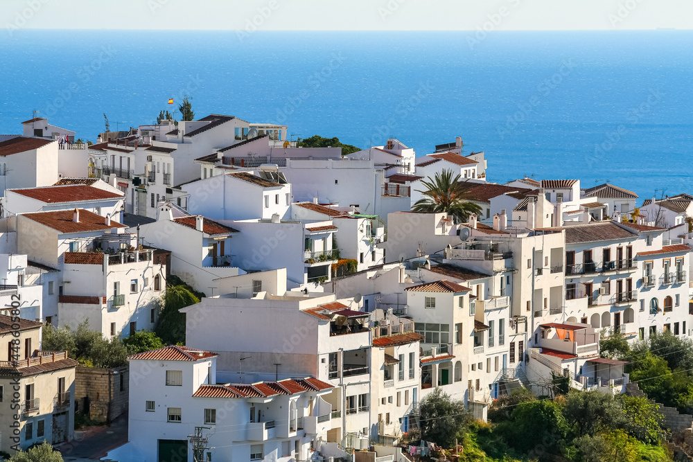 Andalusian white village on a hill and overlooking the blue sea in the background. Frigiliana Malaga.