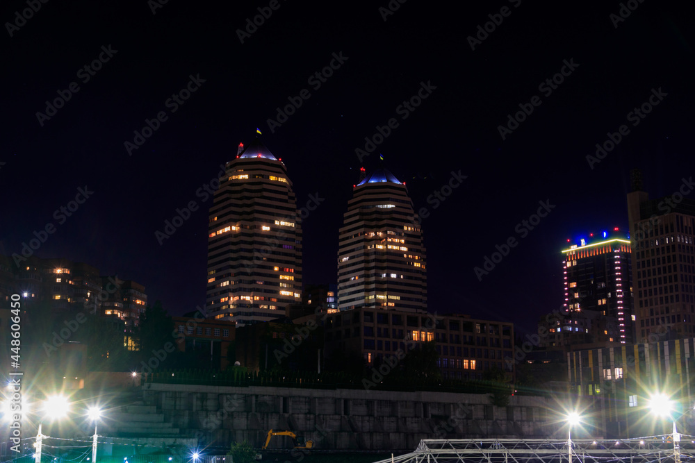 View of beautiful modern buildings, skyscrapers and towers of the night big city in Dnipro, Ukraine