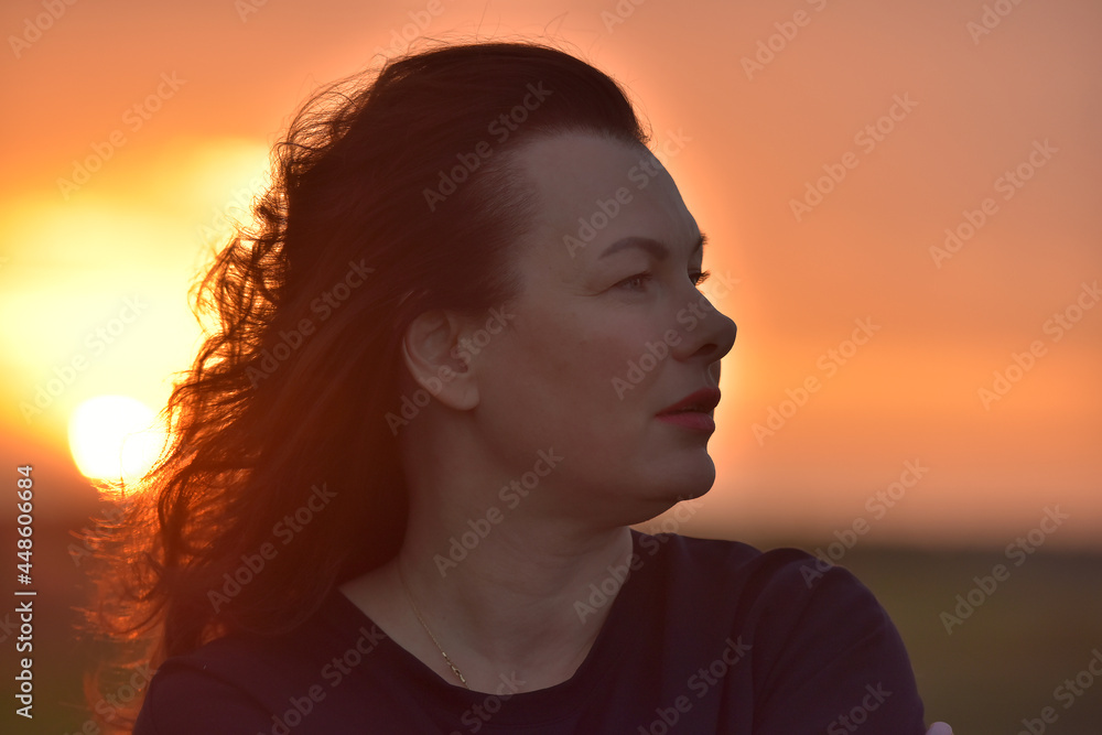 portrait of a red-haired woman in the evening against a sunset portrait of a red-haired woman in the evening against a sunset