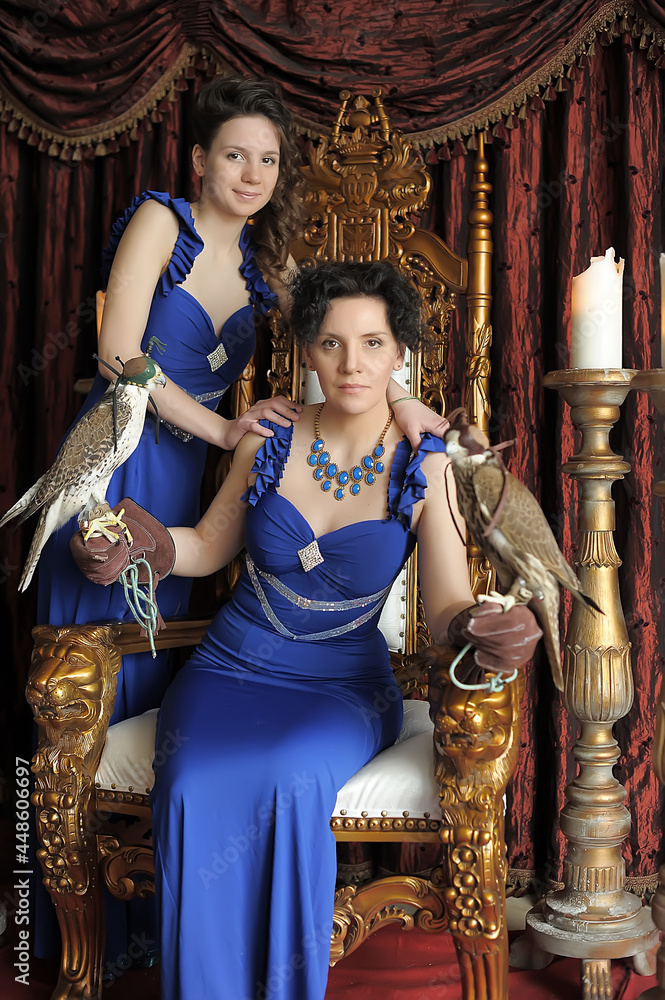 two brunette women princess and queen in blue dress on the throne