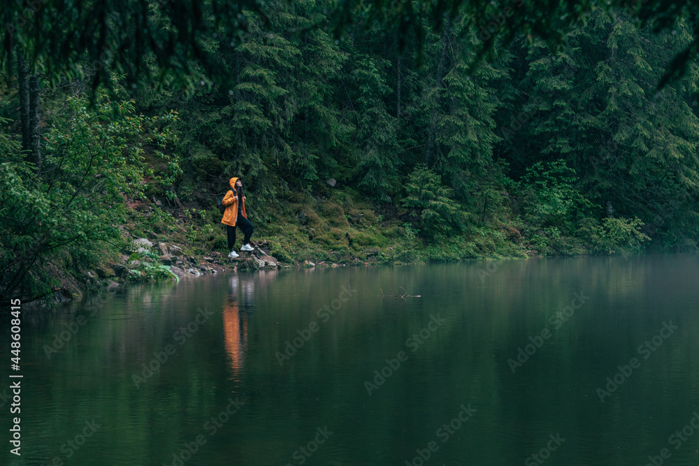 woman hiker in yellow raincoat at lake beach woman hiker in yellow raincoat at lake beach