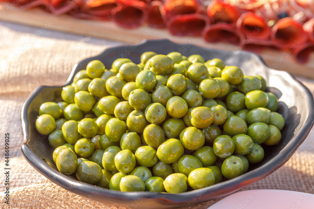 Green pickled olives are lying in a metal bowl. Green pickled olives are lying in a metal bowl.