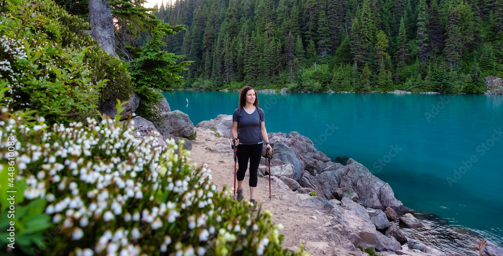 Fototapeta premium Adventurous White Caucasin Adult Woman Hiking on a trail in Canadian Nature. Sunset Sky. Garibaldi Lake Hike near Whistler and Squamish, British Columbia, Canada.