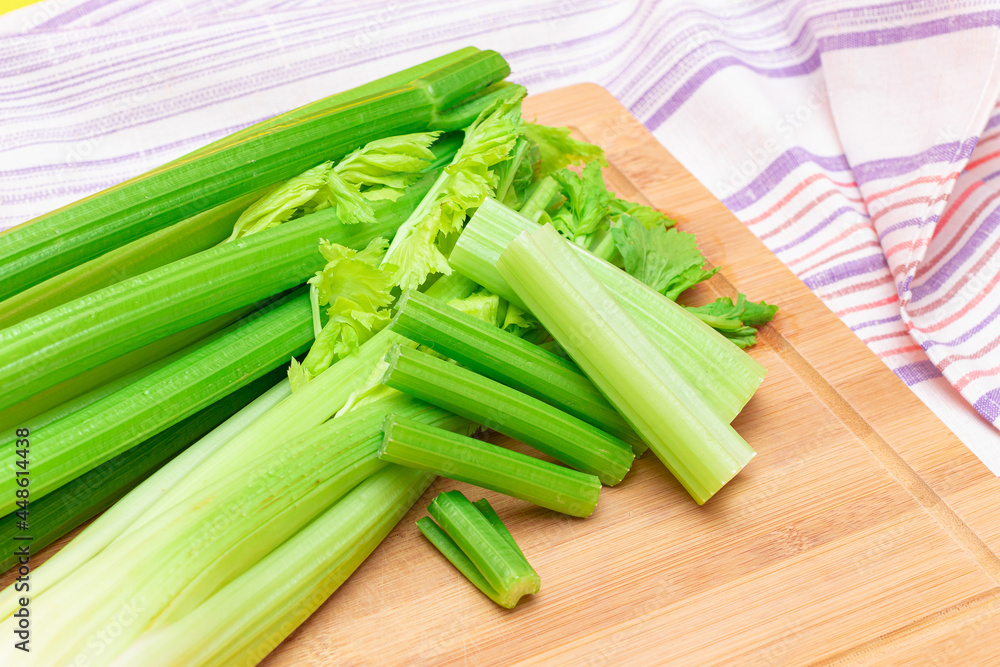 Fresh Celery Stem and Chopped Celery Sticks on Wooden Cutting Board. Vegan and Vegetarian Culture. Raw Food. Healthy Diet with Negative Calorie Content. Slimming Food