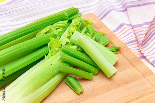 Fresh Celery Stem and Chopped Celery Sticks on Wooden Cutting Board. Vegan and Vegetarian Culture. Raw Food. Healthy Diet with Negative Calorie Content. Slimming Food