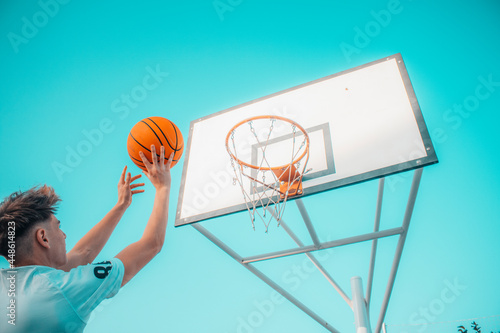 Jugador de baloncesto canastando y saltando con el balón en la pista de juego para ganar puntos © Migue Suarez