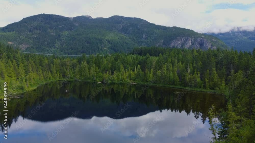Opening aerial shot of the mirror lake surrounded by forest on a sunny morning Opening aerial shot of the mirror lake surrounded by forest on a sunny morning