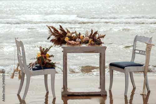 A table  designed for a boho style event with an eucalyptus, vintage plates and other rustic touches. On seaside in the sand dunes