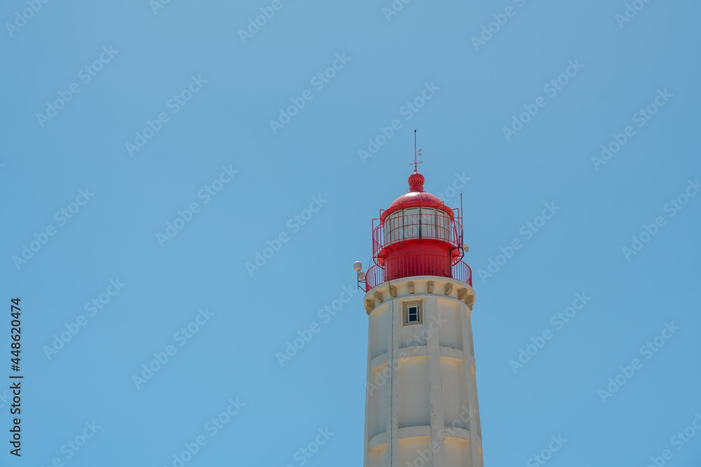 A white lighthouse with a red top, against the blue sky. A conceptual signal for the direction of everything. Copy space