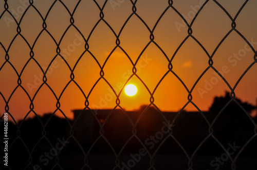 Sunset behind bars. An example of inaccessible happiness